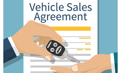 Hand holding a car key for Lease in front of a loan contract agreement