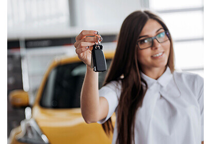 Leasing a car made simple with a female holding car keys in front of a yellow car