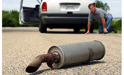 a man on the ground trying to find the cars muffler