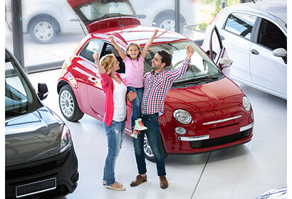 excited family standing next to a new car